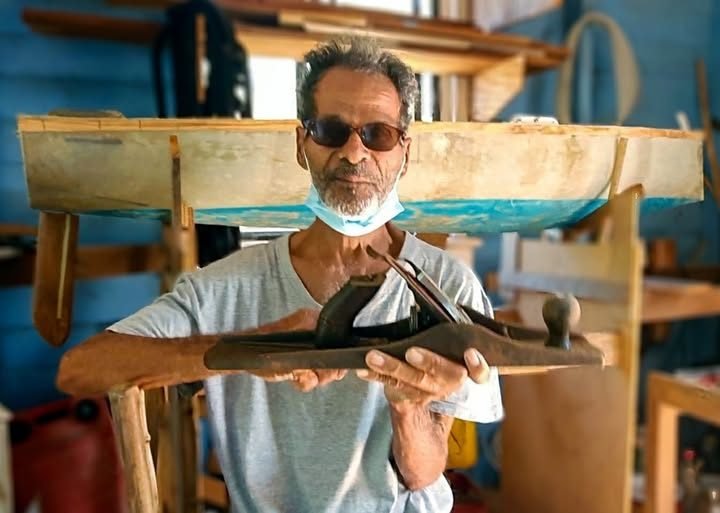 Baldwin « Balo » DeRoche tenant une maquette de demi-coque dans son atelier
