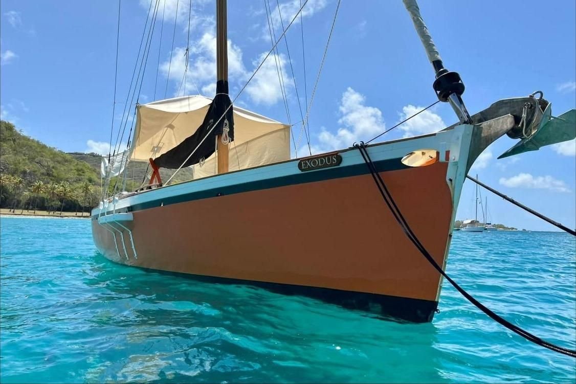 Exodus au mouillage : coque orange, listons turquoise