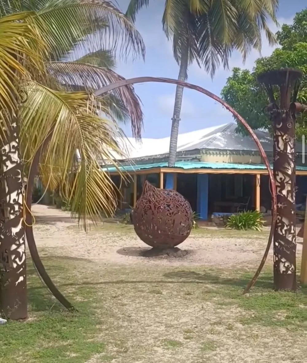 Le studio d’Aragorn Dick-Read à Trellis Bay : une sphère de métal ajourée posée sous une arche, entre deux totems découpés, devant l’atelier
