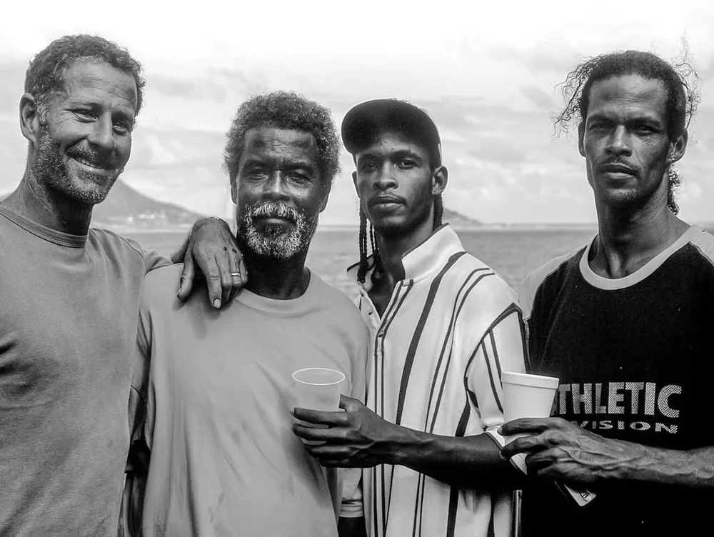 Alexis Andrews, Alwyn Enoe et deux de ses fils posent au bord de la mer, un verre à la main