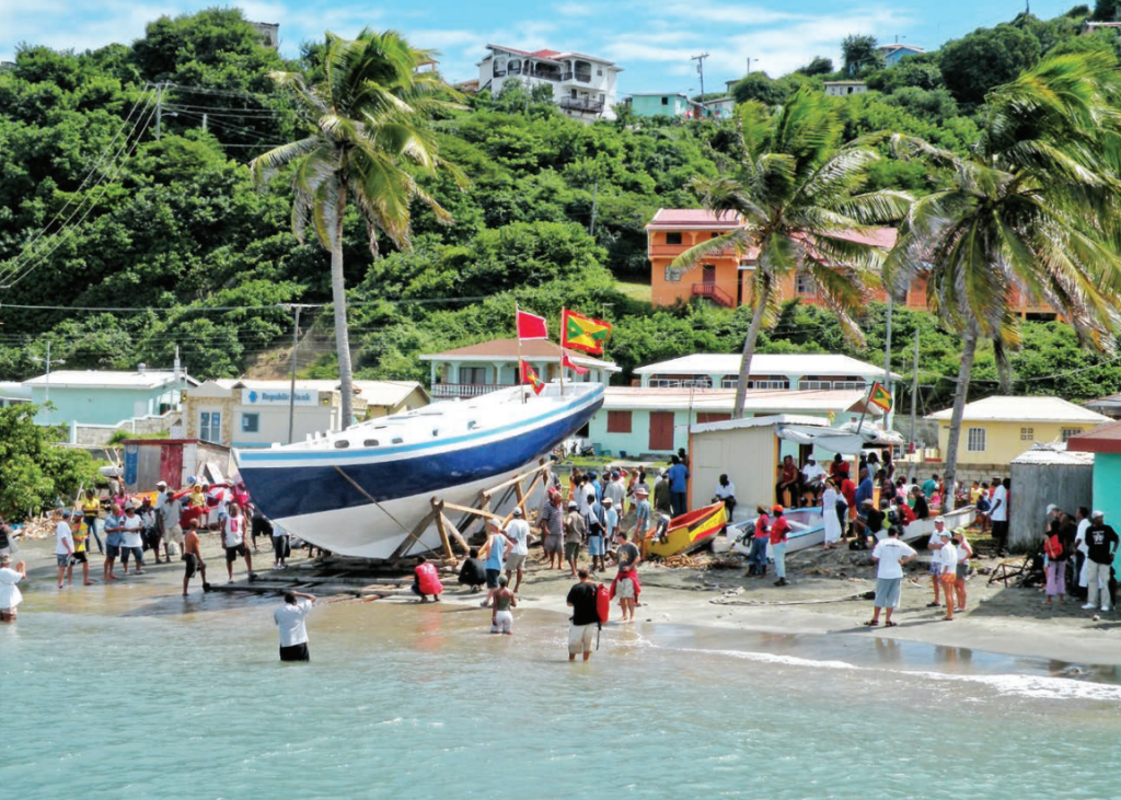 Lancement du sloop Beauty of Petite Martinique sur la plage, devant la foule du village