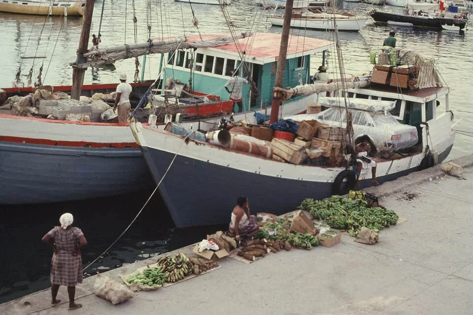Deux sloops de charge accostés au quai de Gustavia, marchandises débarquées sur le pavé