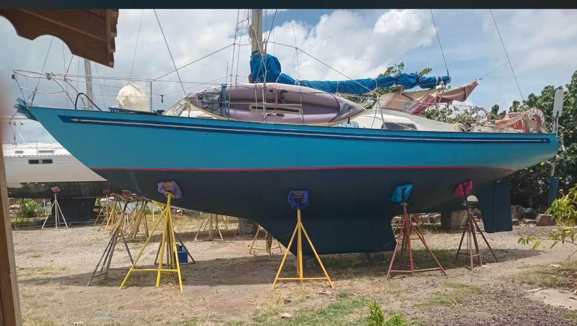 Le voilier Ciganka, un Rival 34 à coque bleue en fibre de verre, calé sur bers dans un chantier à terre de Carriacou, une annexe pneumatique arrimée à bord