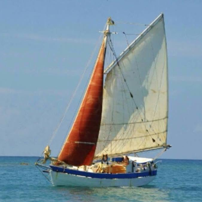 Le sloop Mermaid of Carriacou sous voiles sur une mer turquoise, grand-voile aurique ocre et coque blanche à liseré bleu