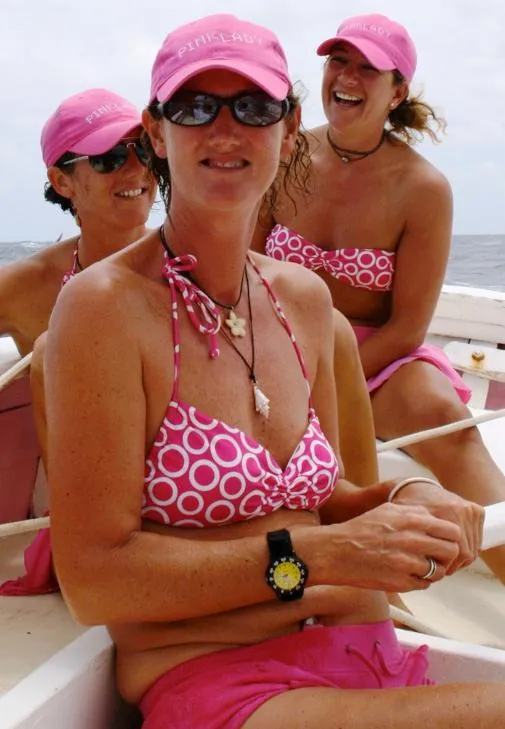 Trois équipières de Pink Lady en casquettes roses à bord du sloop