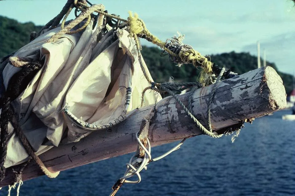 La bôme d’un sloop et sa grand-voile ferlée, serrée par des garcettes