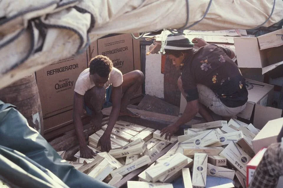 Deux hommes rangent des cartons dans la cale d’un sloop de charge